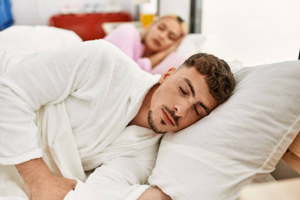 Młoda kaukaska para śpiąca na łóżku w domu. - Zdjęcie, obraz