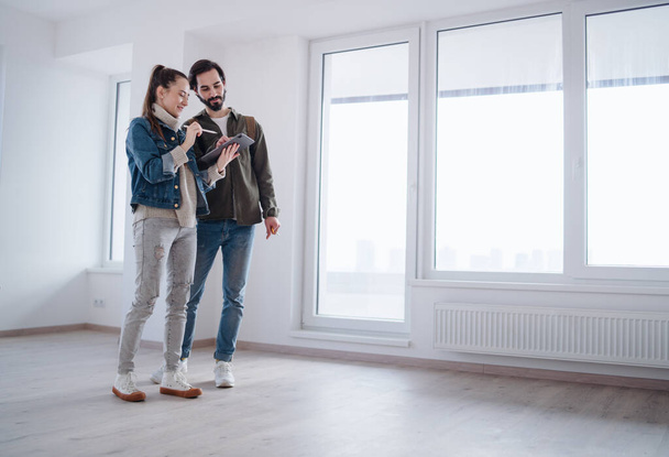Young couple with tablet moving and planning in new flat, new home and relocation concept. - Foto, Imagem