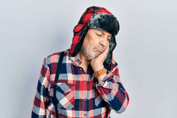 Handsome mature man wearing winter hat with ear flaps thinking looking tired and bored with depression problems with crossed arms.  - Photo, Image