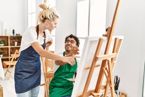 Profesor de pintura mujer enseñando a estudiante hombre en el estudio de arte. - Foto, imagen