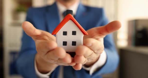 Muž pojišťovací agent drží malý dům v rukou 4k film - Záběry, video