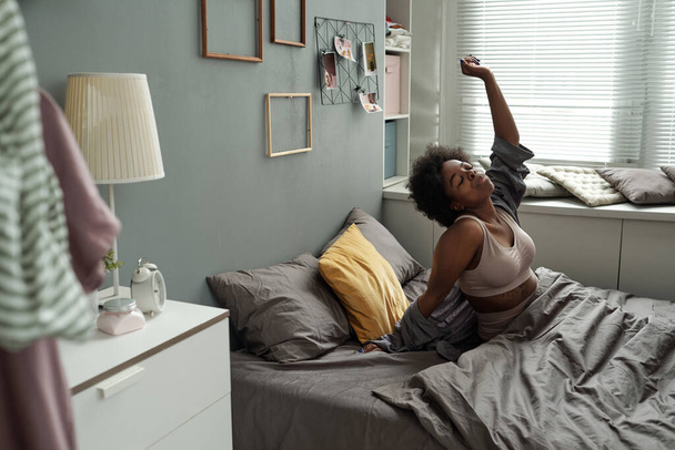 Young African woman stretching in bed in the morning - Foto, Bild