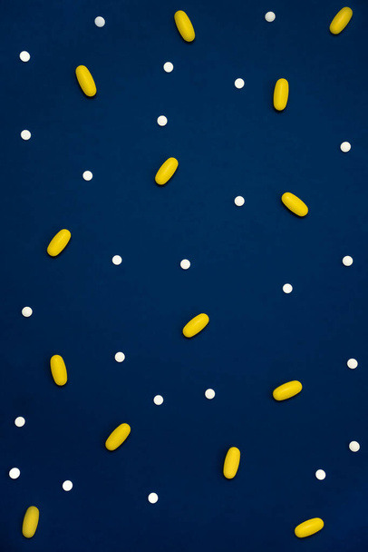 Vielzahl von Medikamenten in Kapseln und Pillen in verschiedenen Farben auf blauem Hintergrund - Foto, Bild