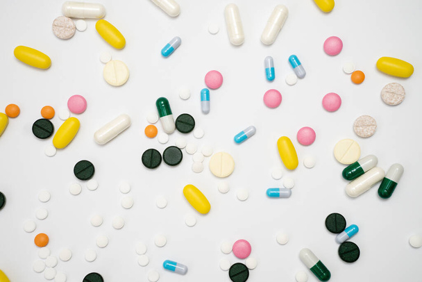 Різноманітність ліків у капсулах та таблетках різних кольорів на білому тлі
 - Фото, зображення