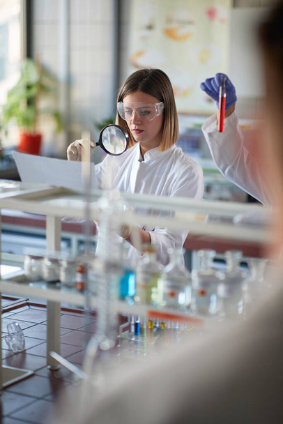 Lab technician working in lab with magnifying glass   - Фото, зображення