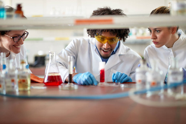 Satisfied lab workers looking chemical reaction in glassware - Foto, Bild