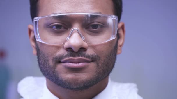 Медленное движение индийского ученого в очках, смотрящего на камеру в лаборатории  - Кадры, видео