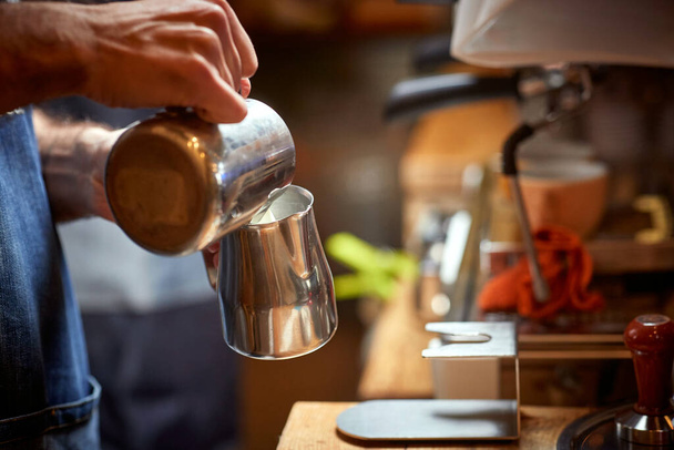 A barman is preparing a milk to make an aromatic and fragrant espresso in the apparatus. Coffee, beverage, bar - Photo, image