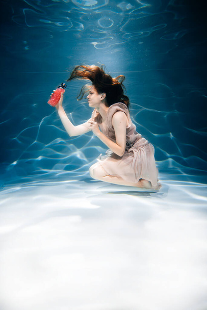 Fitness girl with colorful smoothie. Freshness under water, swims and dives. - Foto, Imagem