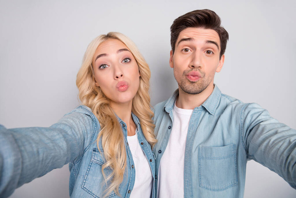 Photo of pretty charming young couple dressed jeans shirts tacking selfie sending you kiss isolated grey color background - Foto, afbeelding