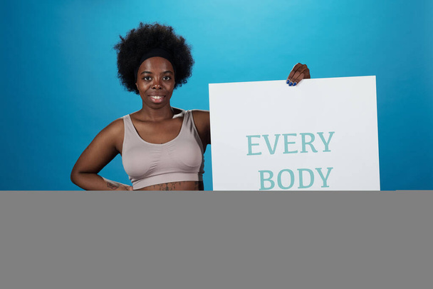Feliz activo más tamaño mujer sosteniendo cartel diciendo thet cada cuerpo es hermoso - Foto, Imagen
