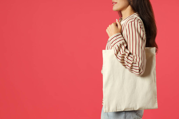 Attractive girl holds cotton bag on pink background, space for text. - Fotoğraf, Görsel