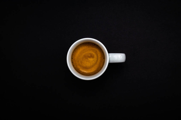 Za każdą odnoszącą sukcesy osobą stoi spora ilość kawy. Widok na blat białego kubka świeżo zaparzonego espresso na ciemnym tle łupku. - Zdjęcie, obraz