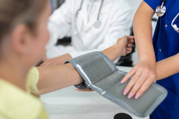 A nurse prepares a patient for a blood pressure test. - Фото, изображение