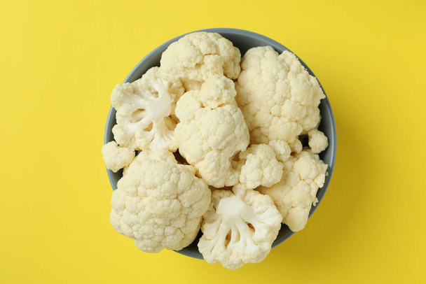 Fresh juicy cauliflower slices in bowl on yellow background - Photo, Image
