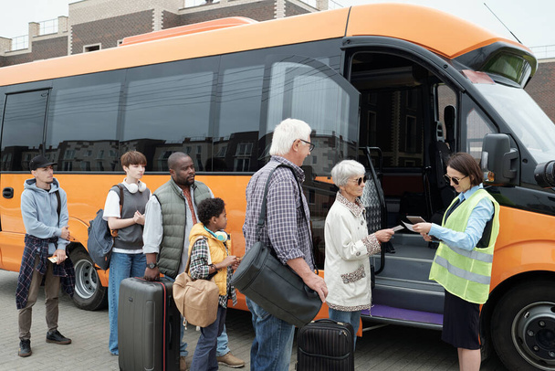Genç otobüs kondüktörü biletleri aracın açık kapısından kontrol ediyor. - Fotoğraf, Görsel