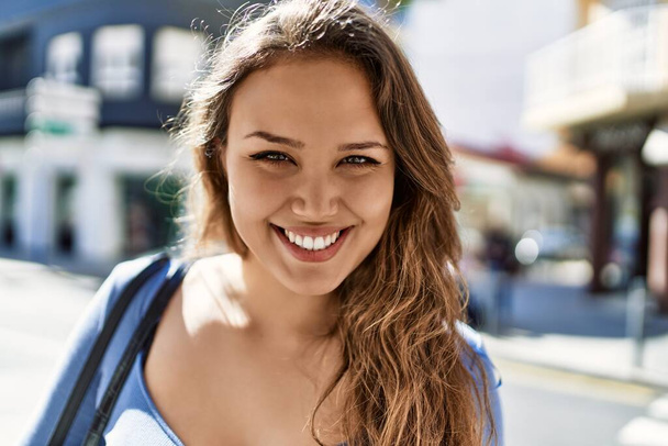 Junges hispanisches Mädchen lächelt glücklich in der Stadt. - Foto, Bild