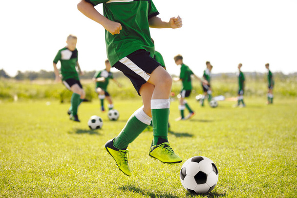 Boy on Grass Campo de fútbol corriendo rápido, saltando y pateando pelota. Equipo de fútbol en la Unidad de Entrenamiento. Equipo de Fútbol Juvenil en Campamento de verano - Foto, imagen