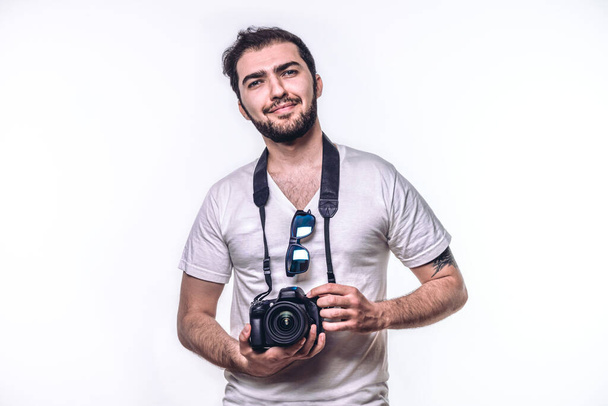 Egy férfi kamerával. A hippi fotós a stúdióban fényképez. Elszigetelt fehér háttér - Fotó, kép
