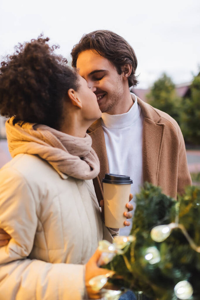 happy multiethnic couple with closed eyes kissing outdoors  - Φωτογραφία, εικόνα