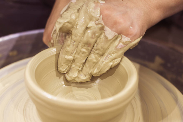 Close-up weergave van vrouwelijke keramiek kunstenaar handen vormen klei op aardewerk wiel.  - Foto, afbeelding