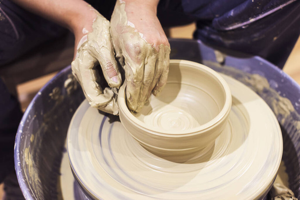 Closeup view of female ceramics artist hands shapes clay on pottery wheel.  - 写真・画像