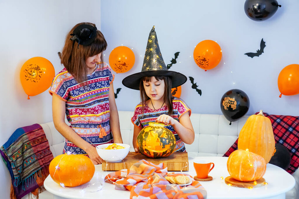 mother and daughter have fun cleaning out insides of pumpkin to make jack o lantern for halloween together - Фото, изображение