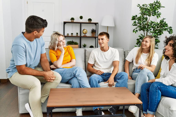Fiatal barátok egy csoportja boldogan mosolyog otthon a kanapén ülve.. - Fotó, kép