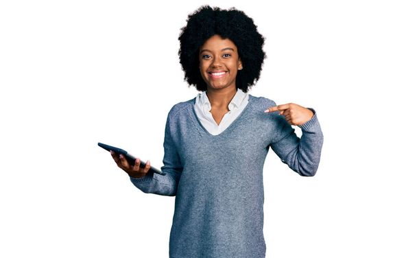 Young african american woman using touchpad device pointing finger to one self smiling happy and proud  - Photo, image