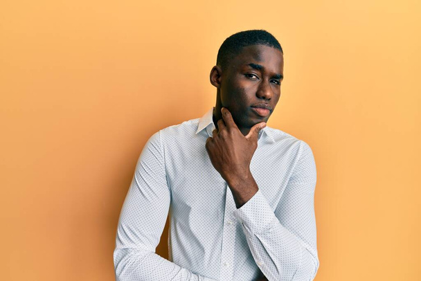 Young african american man wearing casual clothes thinking concentrated about doubt with finger on chin and looking up wondering  - Photo, Image