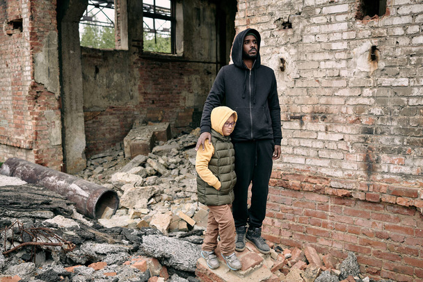 Fiatal férfi és kislány áll a romos épület mellett - Fotó, kép