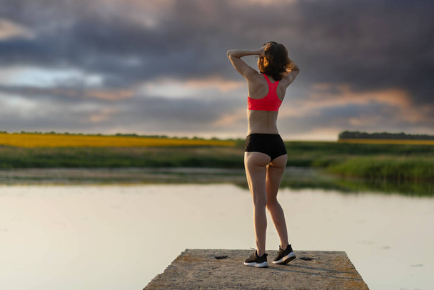 Slender young woman in sports top and shorts back view with copy space. Active lifestyle. - Fotografie, Obrázek