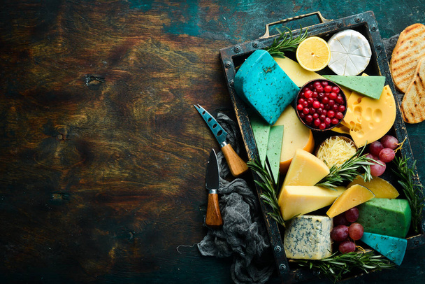 Big set of cheeses with snacks in a wooden box. On a black stone background. Free copy space. - Fotoğraf, Görsel