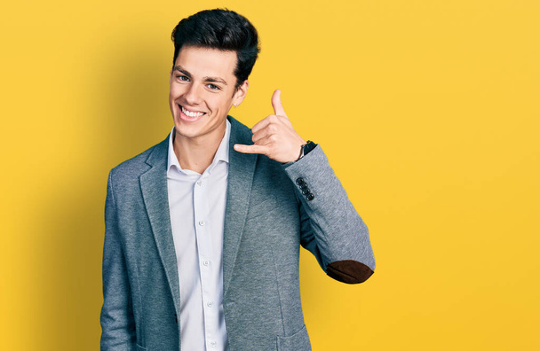 Молодий іспаномовний чоловік в діловому одязі посміхається робити жест телефону з рукою і пальцями, як розмовляти по телефону. концепції спілкування
.  - Фото, зображення