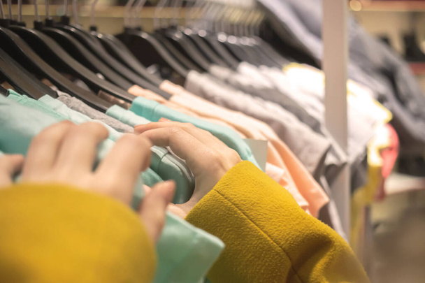 Kobieta patrzy na wieszaki T-shirt w sklepie mody z bliska widok - Zdjęcie, obraz