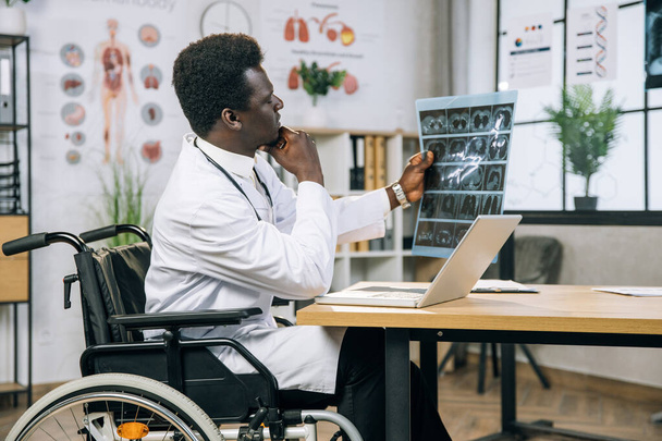 African doctor who using wheelchair examining x ray scan - Foto, imagen