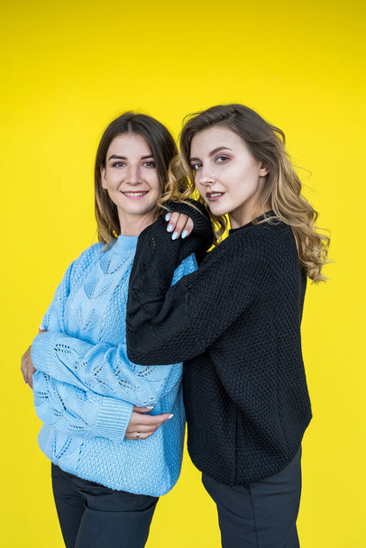 fashionable two young european women posing in knitted sweaters isolated on yellow background. lifestyle - Photo, Image