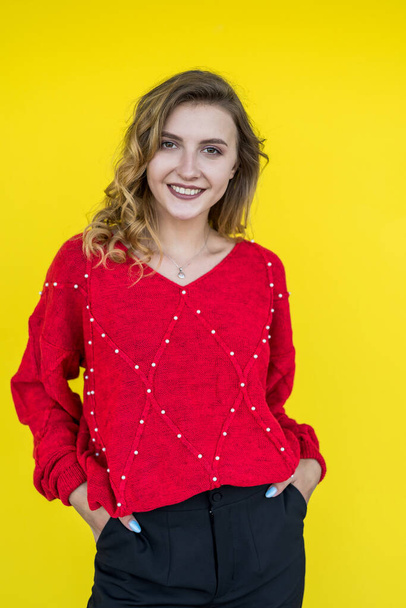 модна жінка в класичному червоному в'язаному светрі позує і посміхається на жовтому тлі. спосіб життя
 - Фото, зображення