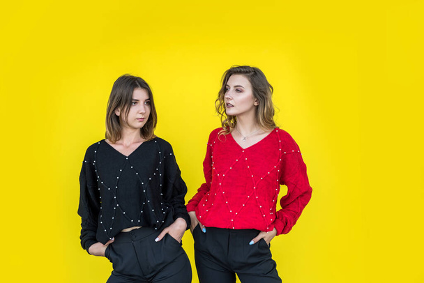 fiatal barátnők pózolnak együtt modern kötött pulóverek elszigetelt sárga fal stúdió portré - Fotó, kép