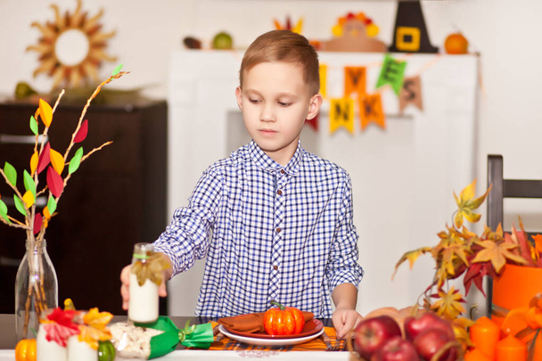 Boy served festive table and decorating living room for celebrating Thanksgiving day. - Foto, immagini