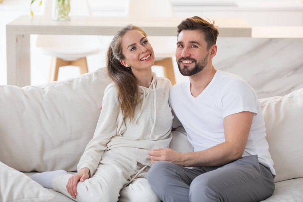 Young beautiful couple smiling sitting on a sofa at home - Foto, Bild