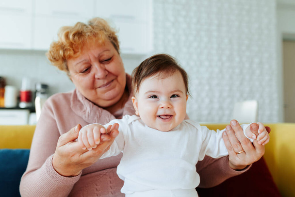 Happy caucasian grandmother playing and holding her little Granddaughter at home - Zdjęcie, obraz