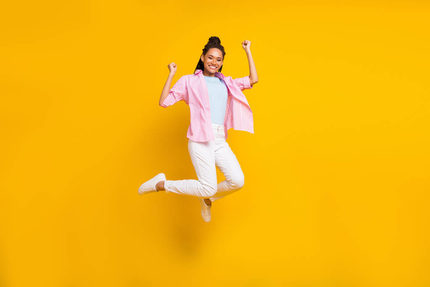 Photo of cheerful lady jump rejoice achievement luck wear striped shirt isolated yellow color background - Foto, Imagen