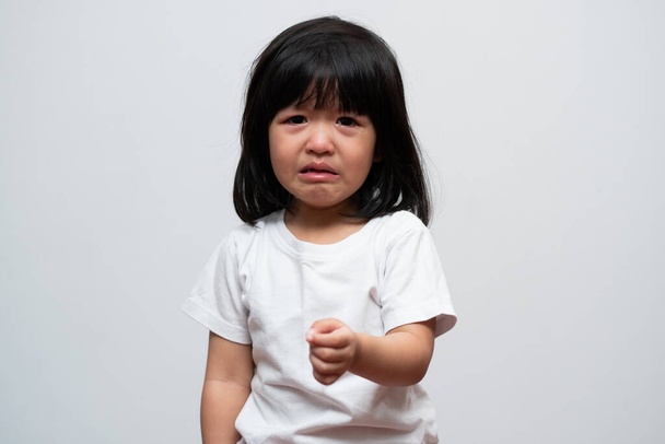 アジアの怒り、悲しいと白い孤立した背景に泣く少女の肖像画は、子供の感情のときに、タントラと狂牛病、表現でこぼこの感情。子供の感情制御の概念 - 写真・画像