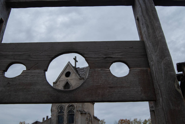 Средневековый блок для наказания преступников на фоне древней церкви. Средневековое оружие - Фото, изображение
