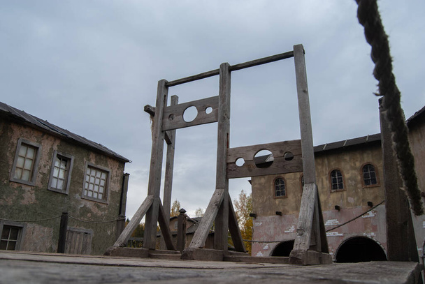 Échafaudage avec deux blocs pour les criminels sur fond de maisons d'une ville médiévale abandonnée. Arme d'exécution médiévale - Photo, image