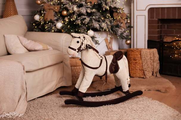 horse rocking chair in Xmas room for child. Cozy xmas Interior home. holiday concept. New Year interior of living room. Christmas interior of room with horse rocking chair and decorated Christmas tree - Fotoğraf, Görsel
