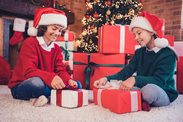 Portrait attraktiver fröhlicher Geschwister Weihnachtsmann Helfer öffnen Verpackung Geschenkboxen Advent Zeit Gelegenheit Fee im dekorierten Loft Interieur Haus drinnen - Foto, Bild