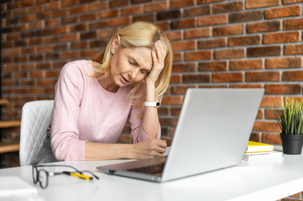 Tired frustrated middle-aged woman using laptop for working - 写真・画像