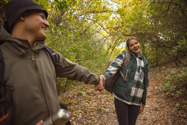 Cropped portrait of happy, joyful couple holding hands, spending time outside the city, doing hiking - 写真・画像